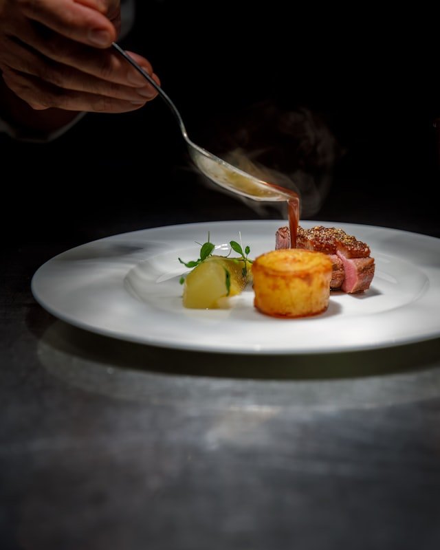 Sauce being poured over a plated course