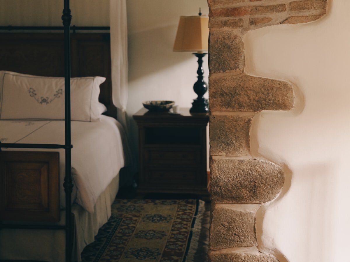 Iron four-poster bed beside a stone archway in the Garden Suite